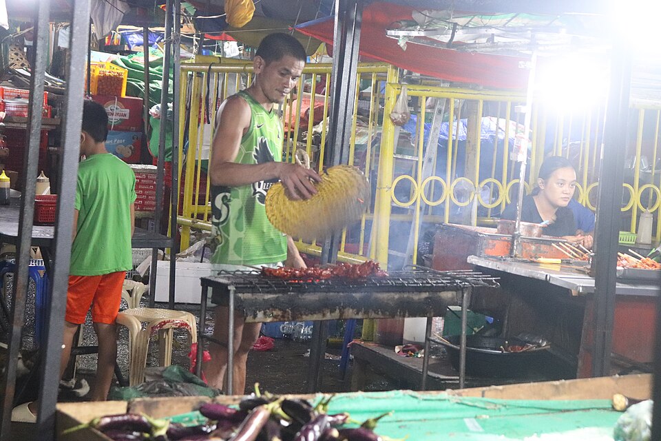 Street food vendor grilling barbecue at Carbon Night Market in Cebu City